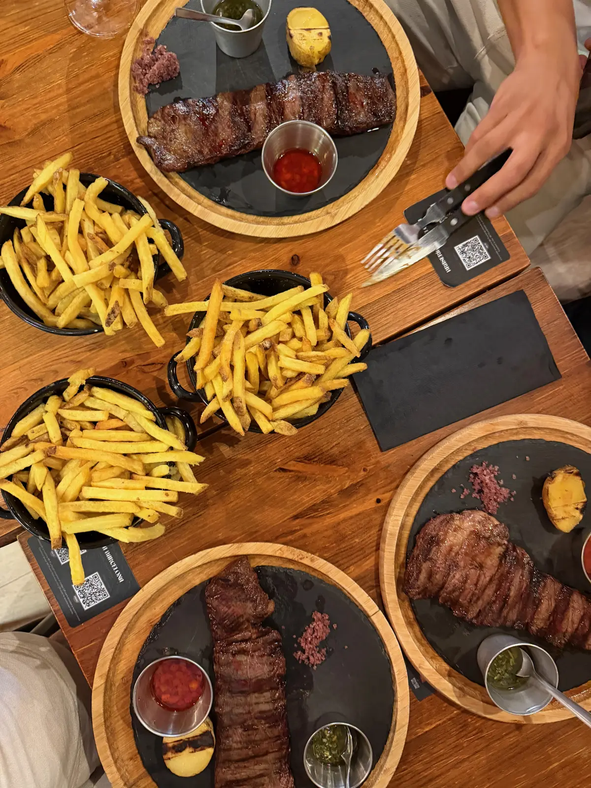 Steaks, chimichurri, salsa and fries in skillets at Braseria Barcelona