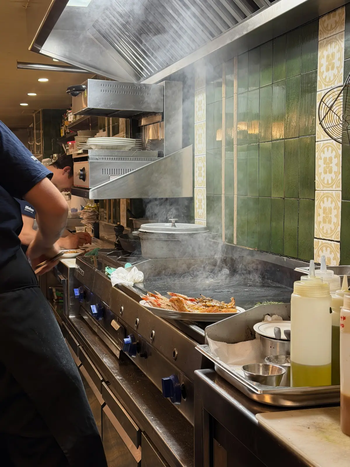 Cooks working the plancha behind the counter at Ultramarinos Marín