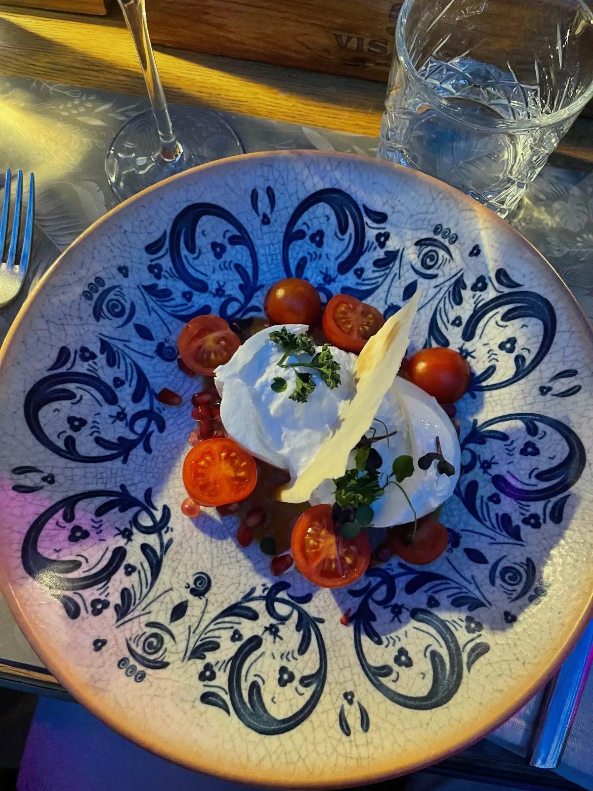 Burrata with cherry tomatoes on a patterned plate at Visage Gastrobar